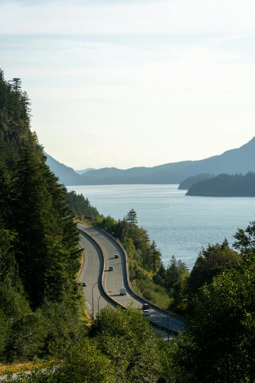 a view looking down on the scenic road in front of water and mountains