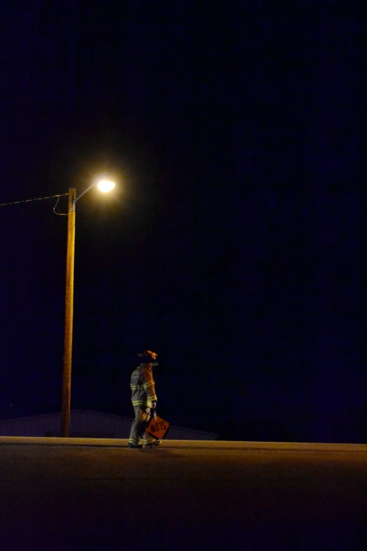 person in the dark standing by a street lamp