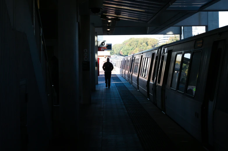 a man walks down the hall between two subway trains