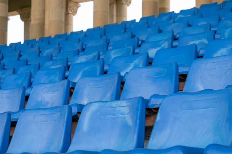 a group of blue chairs sitting in a room next to pillars