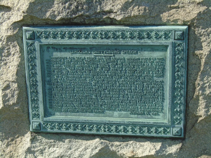a green plaque sitting on the side of a large rock