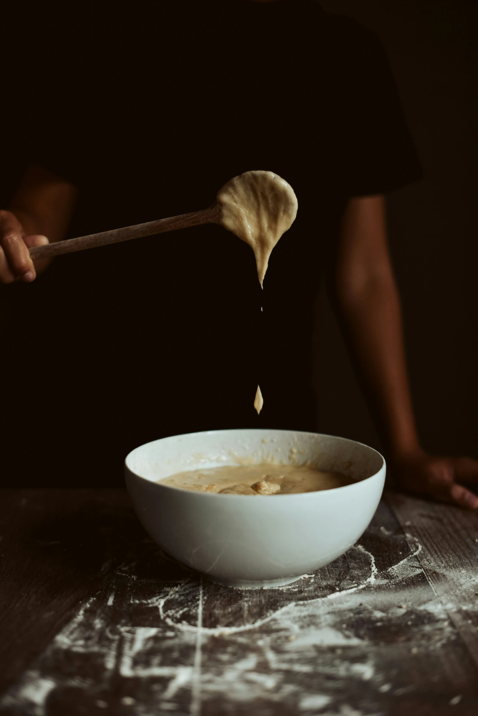 a wooden spoon pouring some batter into a bowl