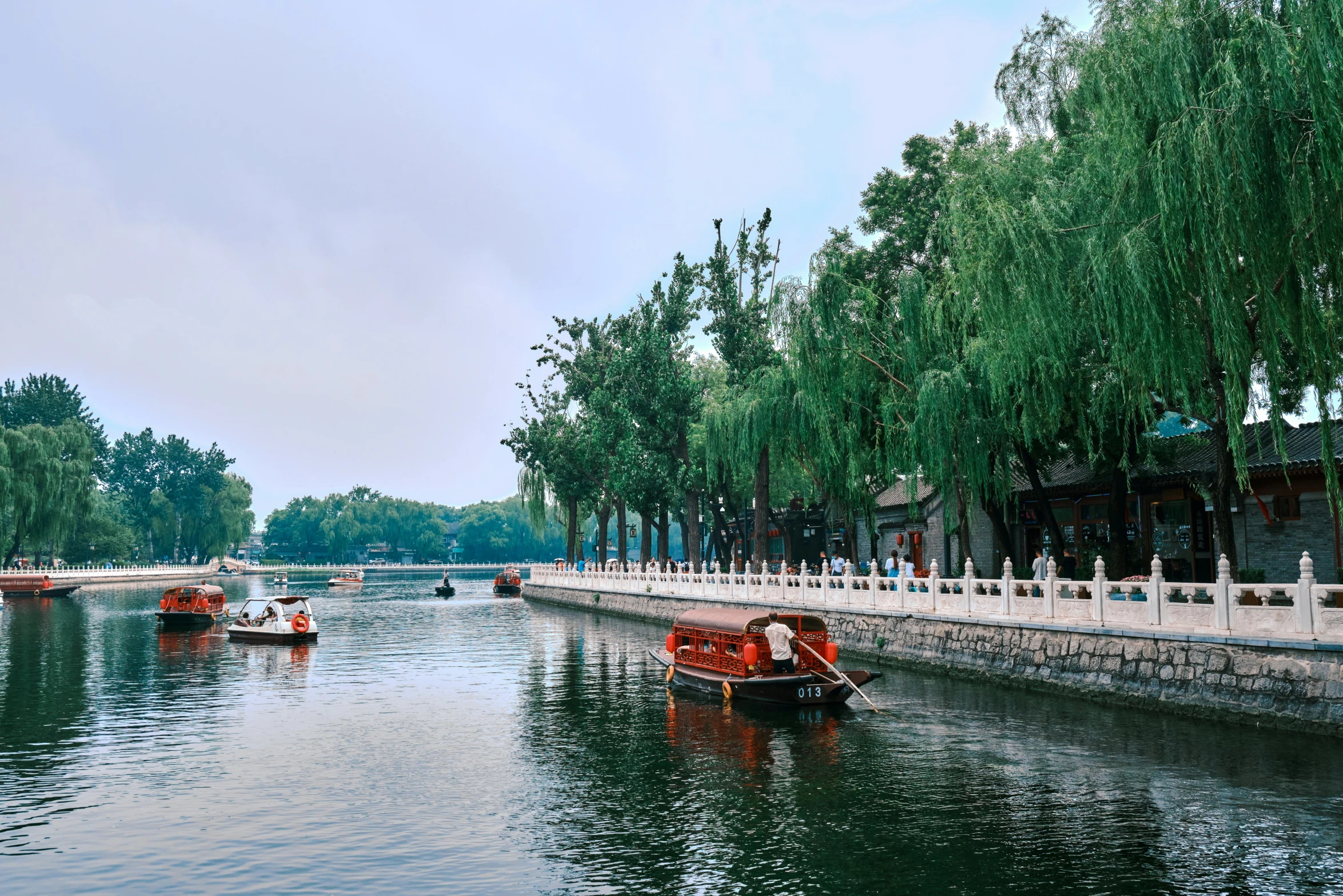 people riding boats on the water next to trees