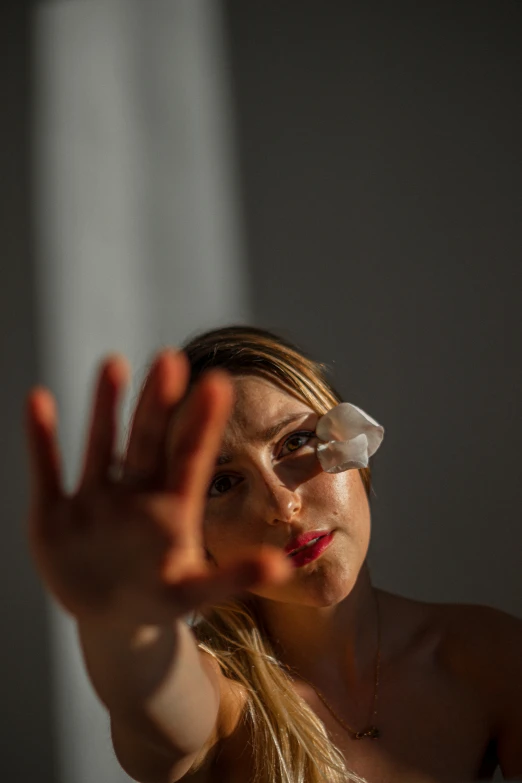 a woman standing in front of a mirror holding her hand up