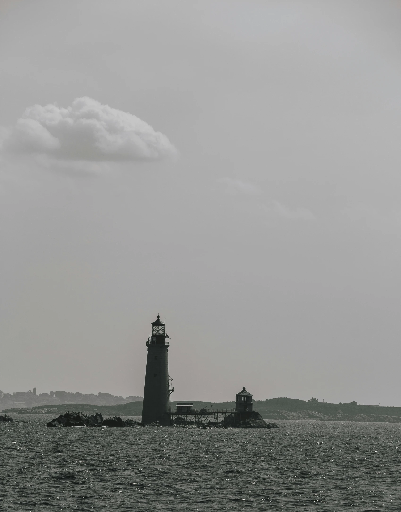 a sail boat sails past a light house