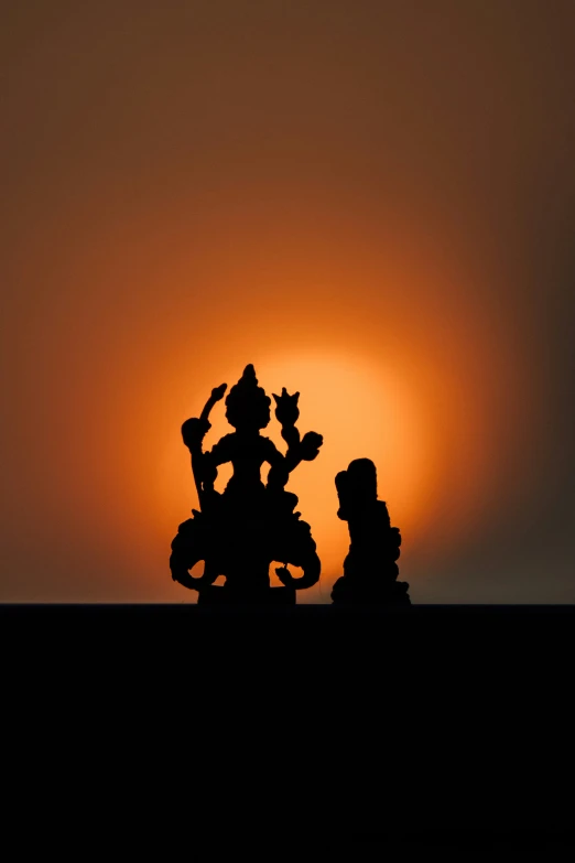 a view of the setting sun behind some statues