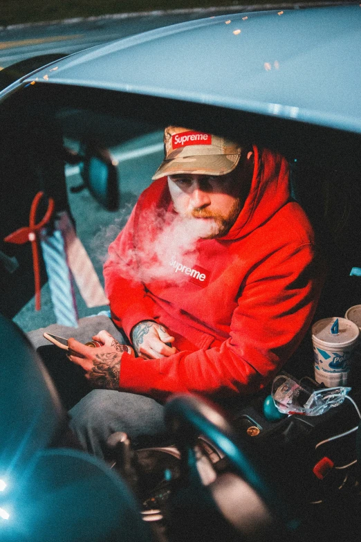 a man in a red hoodie is sitting in his car