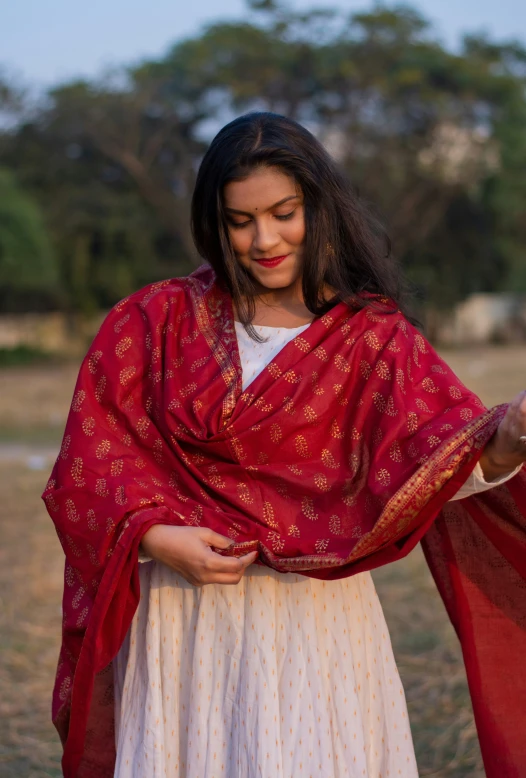 young woman with her arms around herself wearing a red and beige outfit