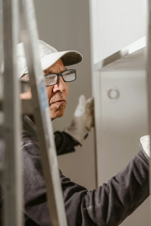 a man wearing glasses and a white hat works on soing