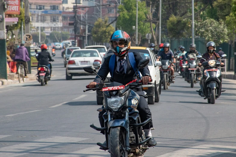 the man rides his motorcycle behind cars on the road