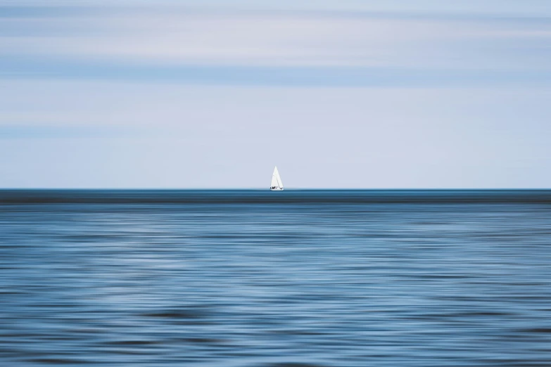 a white boat on blue water with a sky background