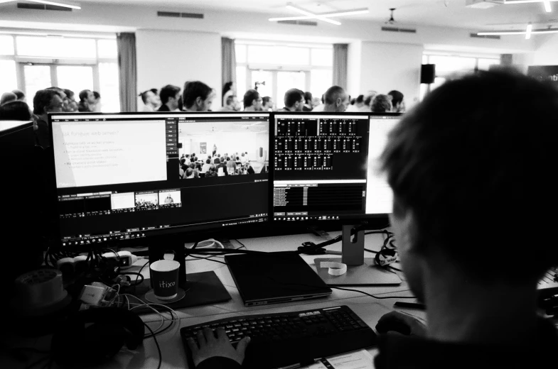 a man sitting in front of two computer monitors