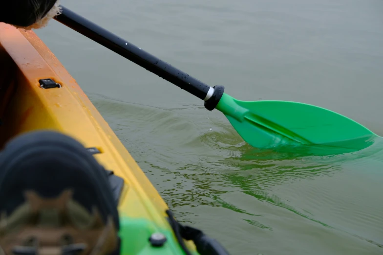 an orange and green kayak paddled by a man in sandals