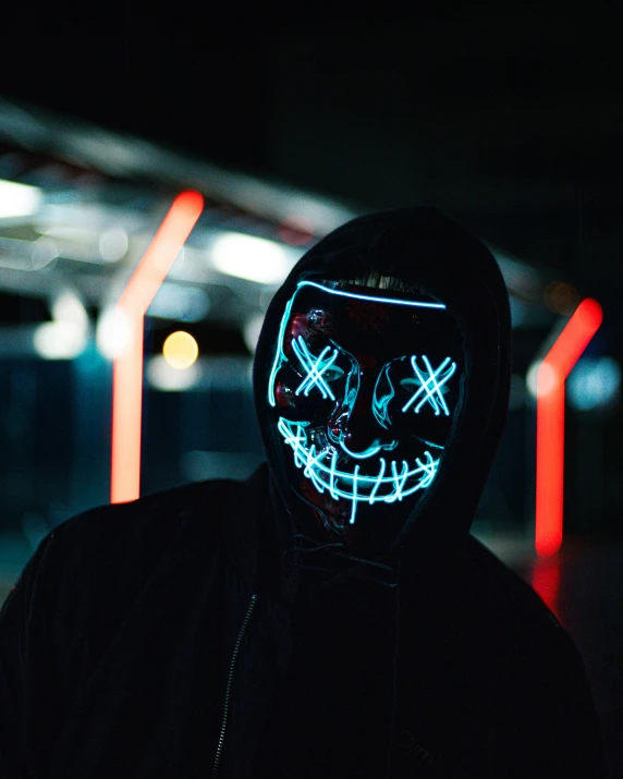 man wearing light up mask standing at night