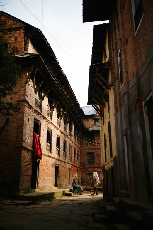 two people sitting on some bricks by some buildings