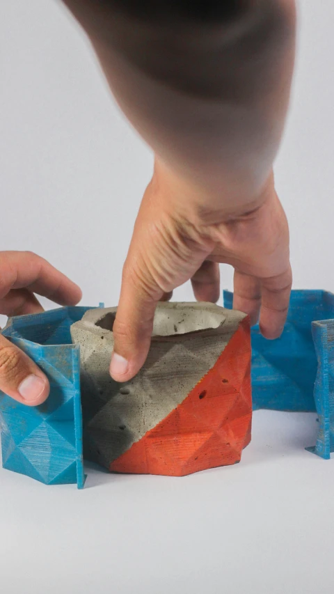 a persons hand touching a fake house made from cement