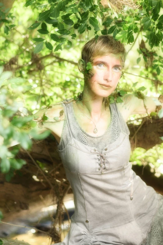 a woman poses for a picture under the green foliage