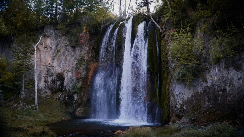 a large waterfall in a rocky area next to trees