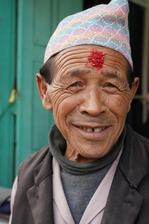 an asian man wearing a colorful hat with a red flower on it's forehead