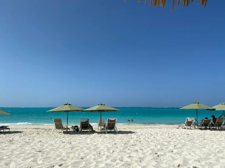 two people lounge under umbrellas on the beach