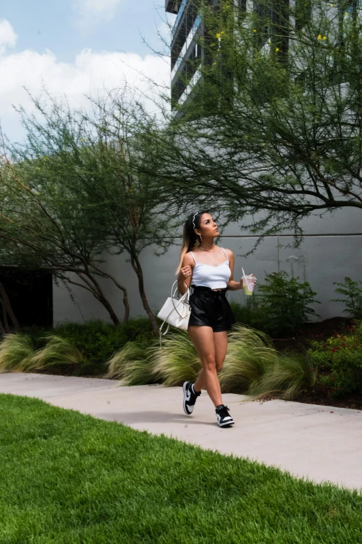 a woman wearing shorts and heels walking with a purse