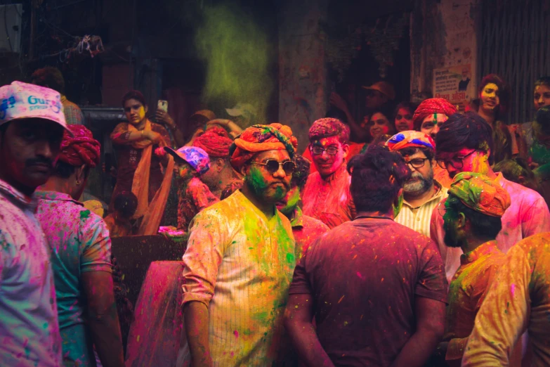 a crowd of people standing around each other covered in color