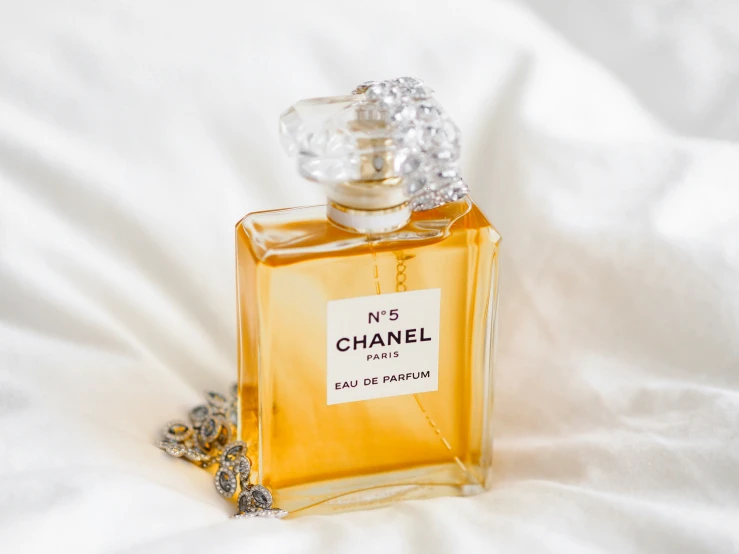 a bottle of chanel perfume sitting on a white sheet