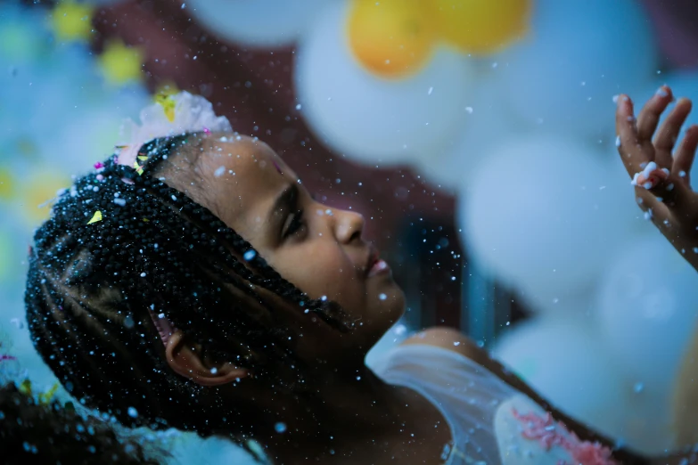 the little girl is looking at the balloons