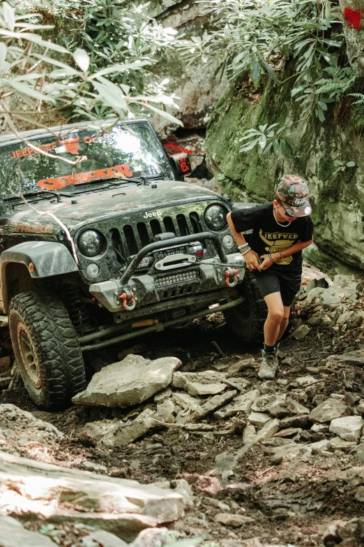 man with a hat on and a jeep on the side of rocks