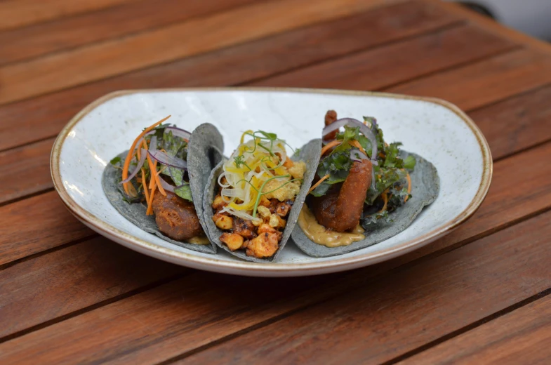 a close up of three tacos on a plate