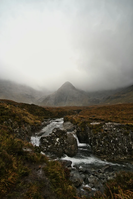 a scenic view of a mountain stream surrounded by fields