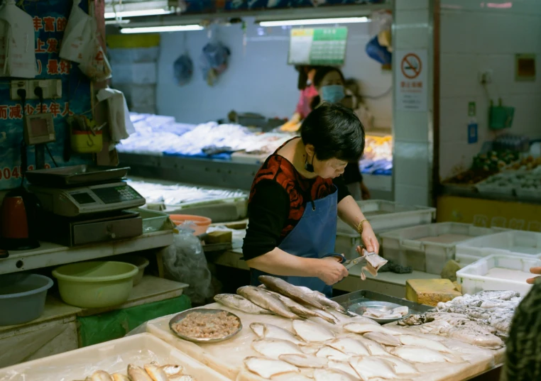 woman making food in a commercial kitchen with several trays of food