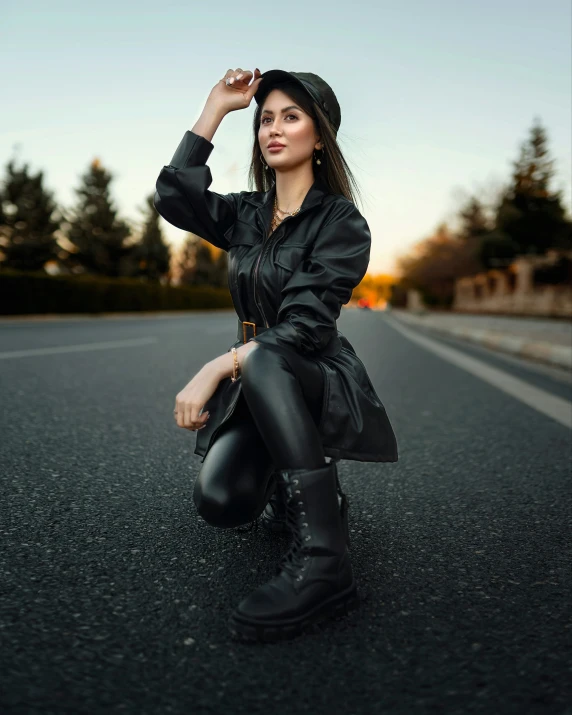 a woman wearing black boots is posing on the street