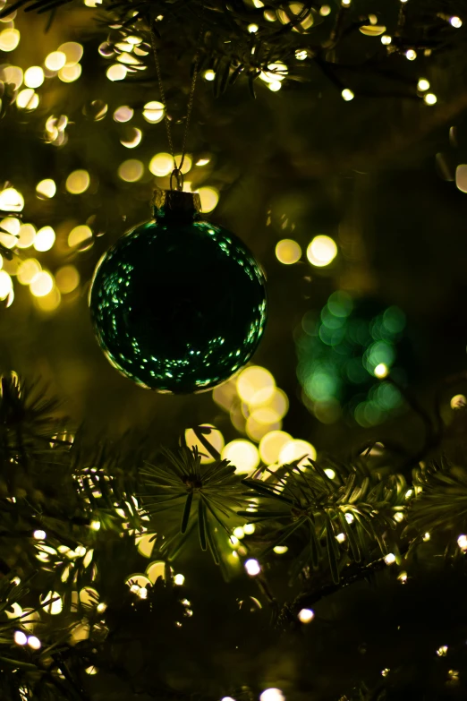 a light - up ball hangs from a green christmas tree