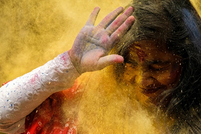 a woman holding her hands in the air while covered with colored powder