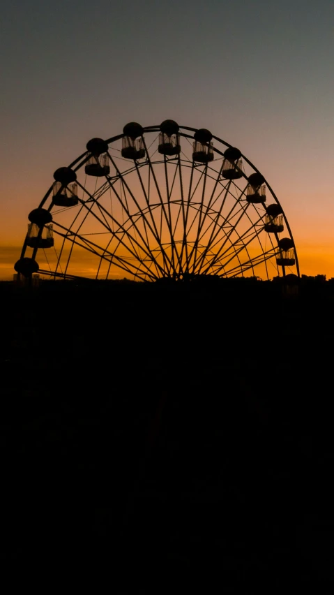 a carnival wheel in silhouette against an orange sunset