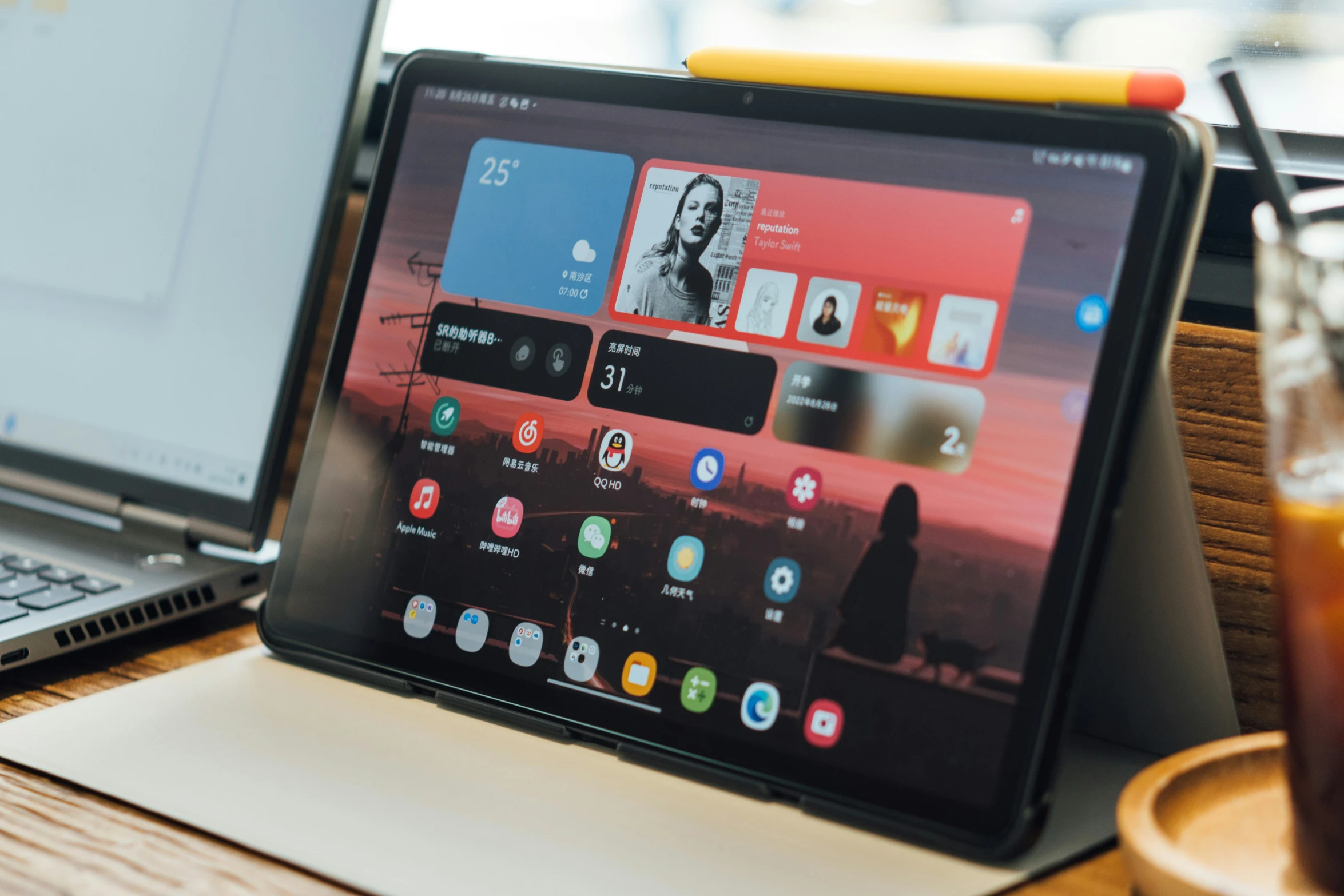 a laptop computer sits next to a drink on a desk