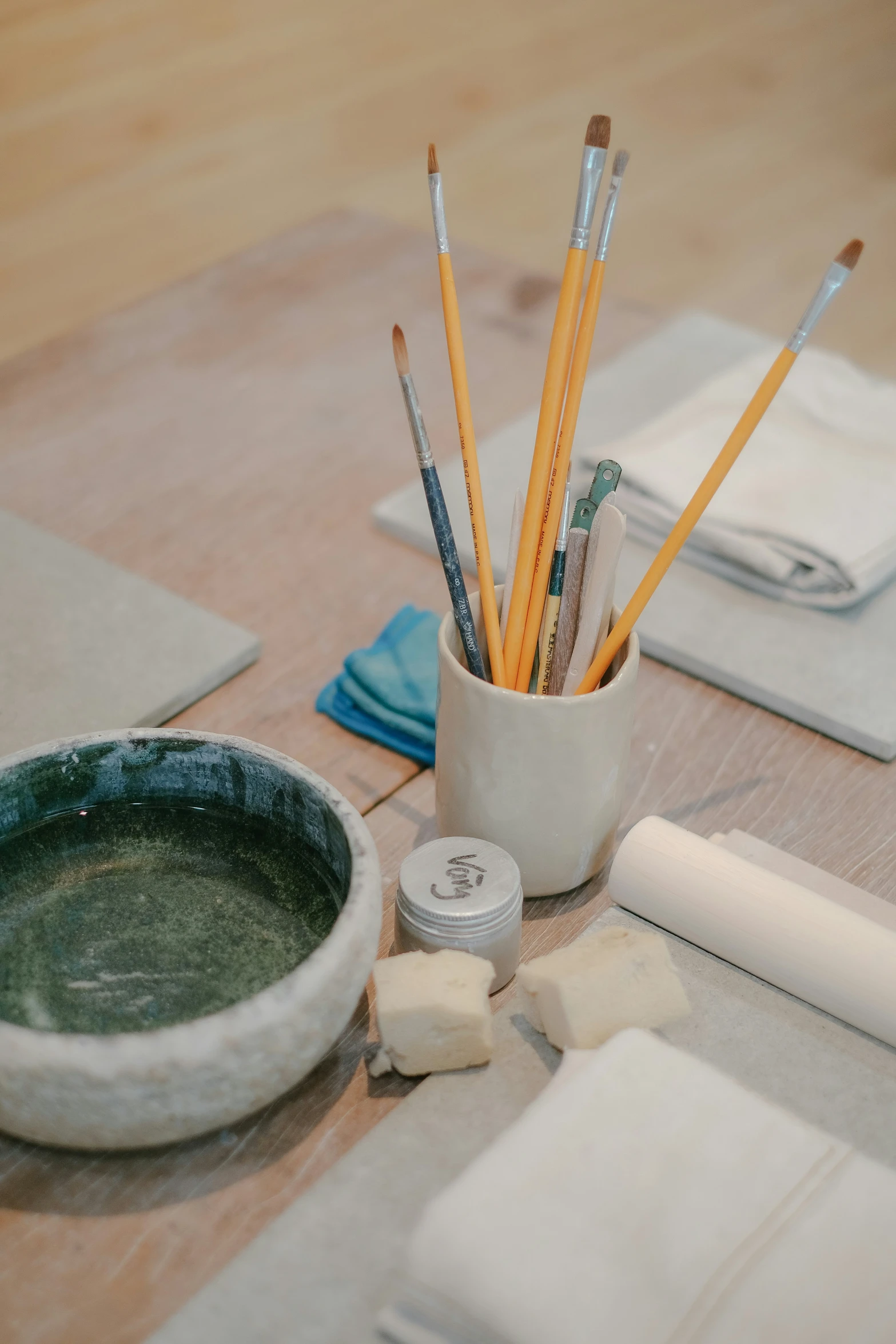 a cup filled with paint and pencils next to some bowls