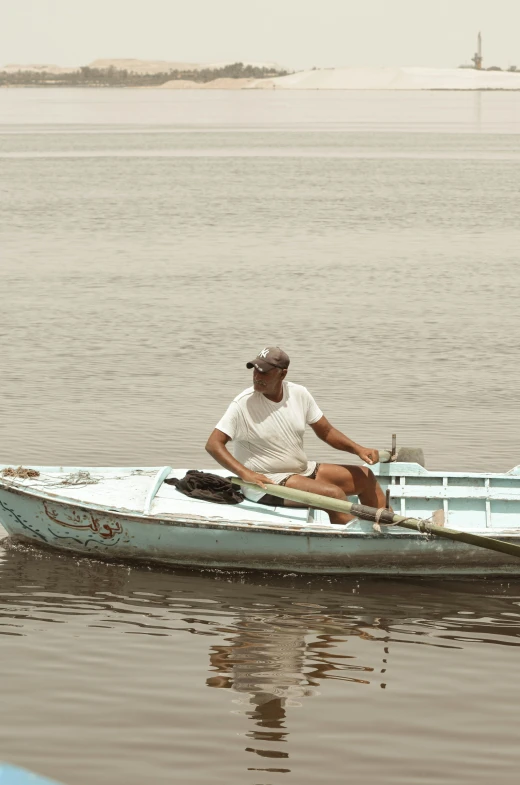man sitting in the front of a row boat in the water