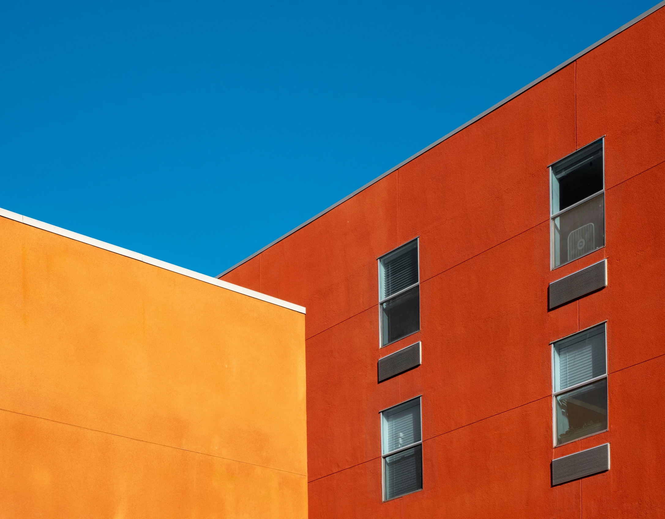 two red buildings that have windows and red walls