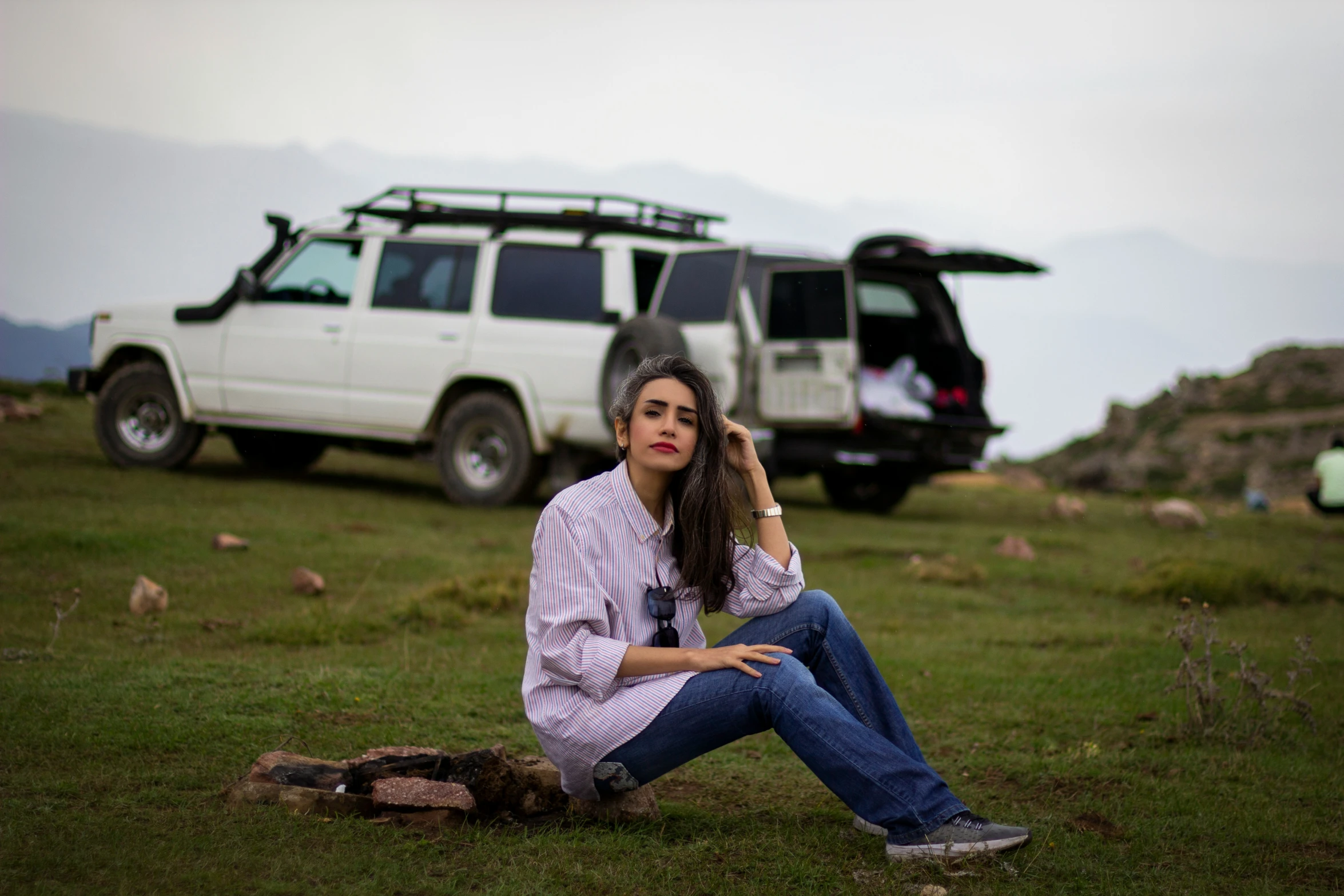 a young woman sitting in the grass while talking on her cell phone