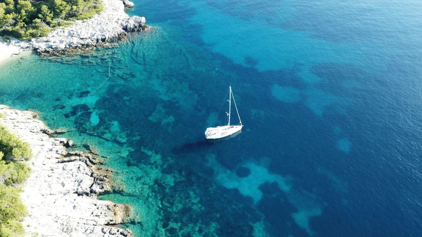 an aerial po of the water around a sailboat