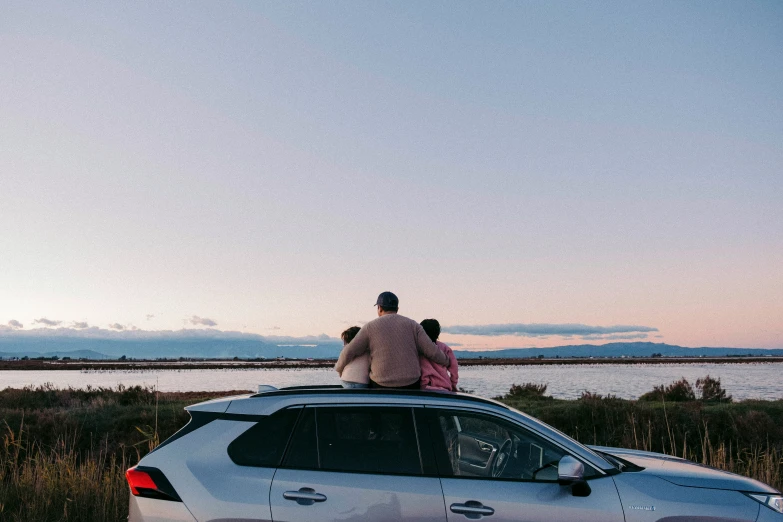 a man and woman sitting on top of a car
