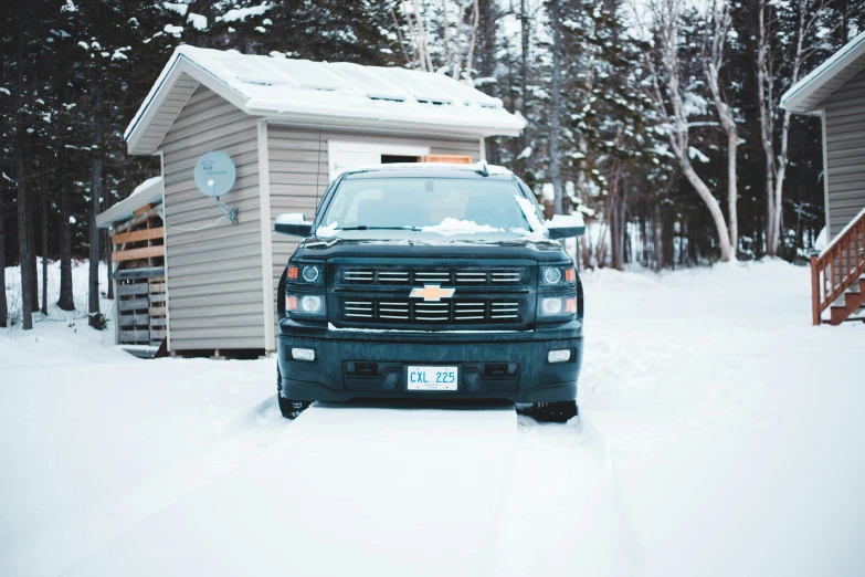 a truck parked outside in the snow near a house