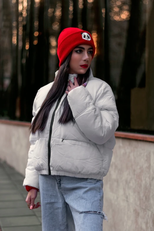 a woman in a jacket and beanie standing outside of a building