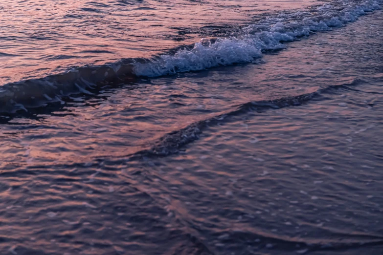 the beach is covered with foam and has waves lapping at it