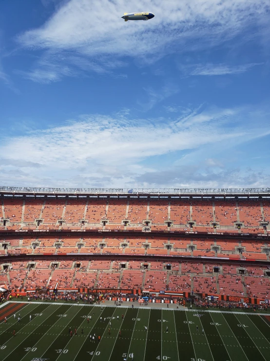 an airplane flying low over a football stadium filled with people