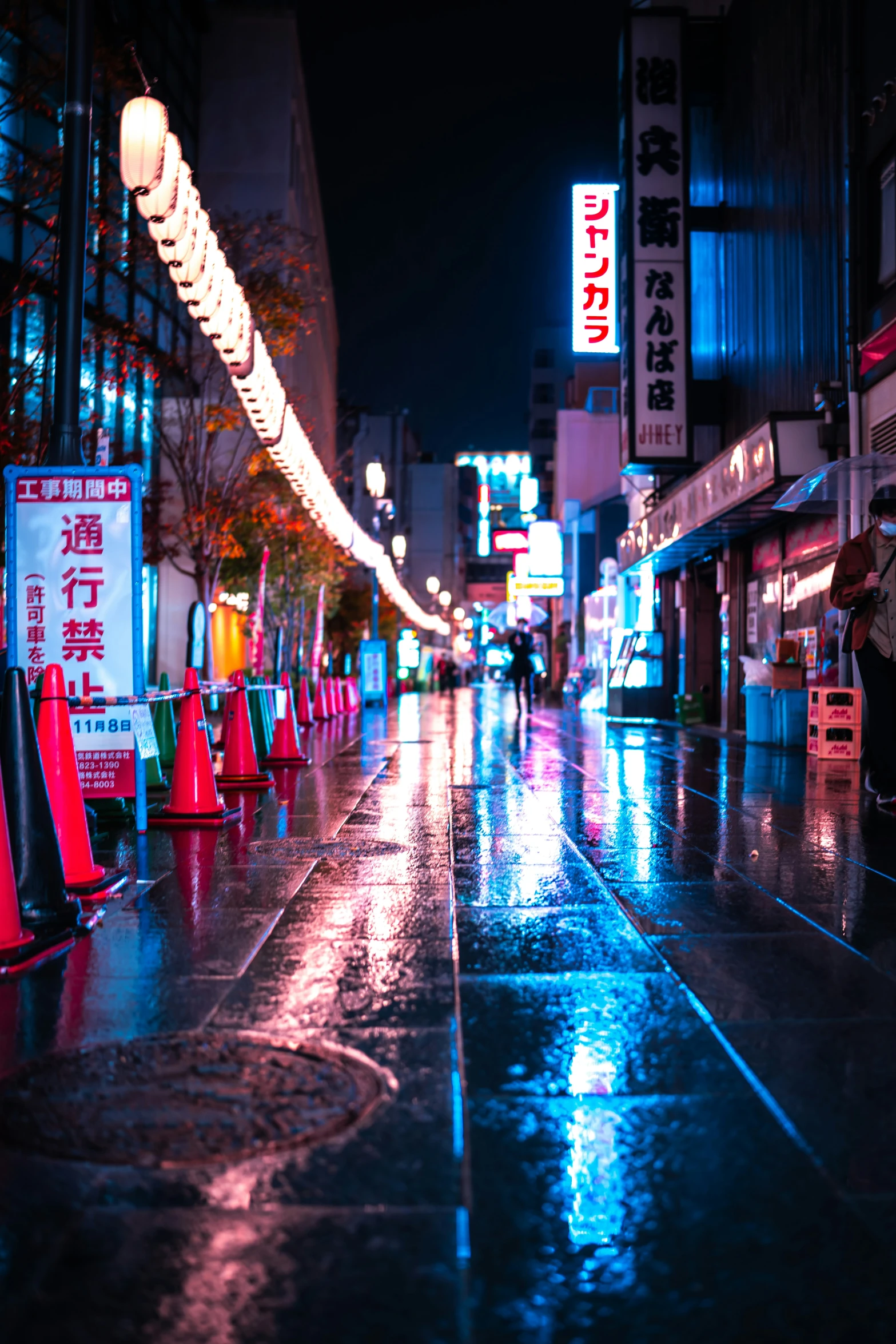 street scene at night with people on the sidewalk, lights and signs