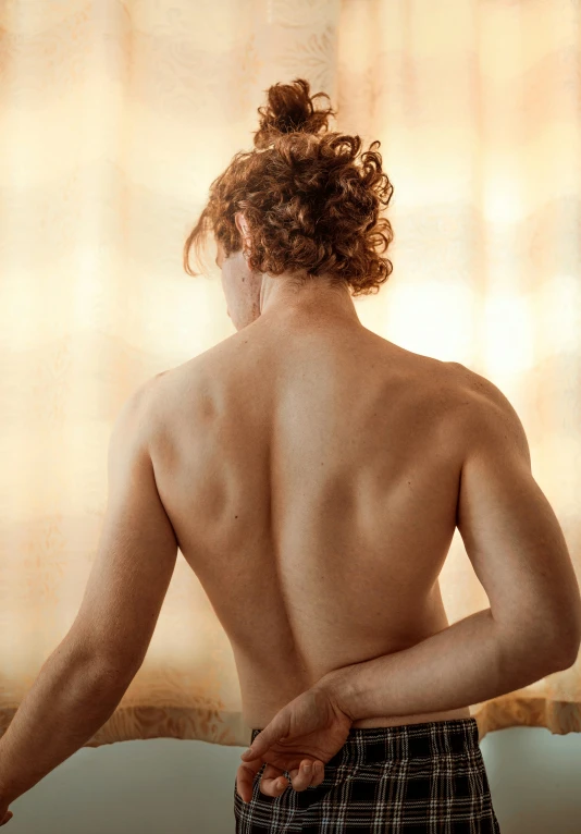 a man standing in front of curtains looking over his back