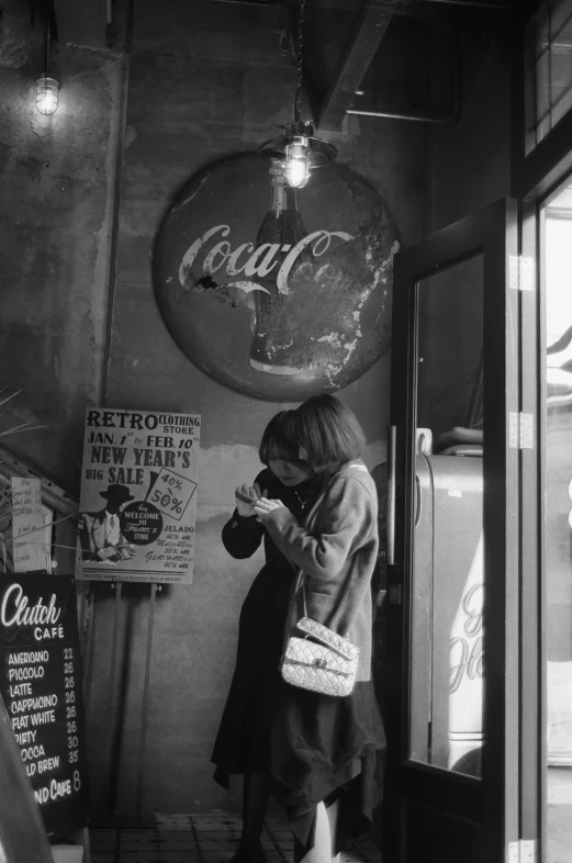 a woman stands at the doorway of a coke shop